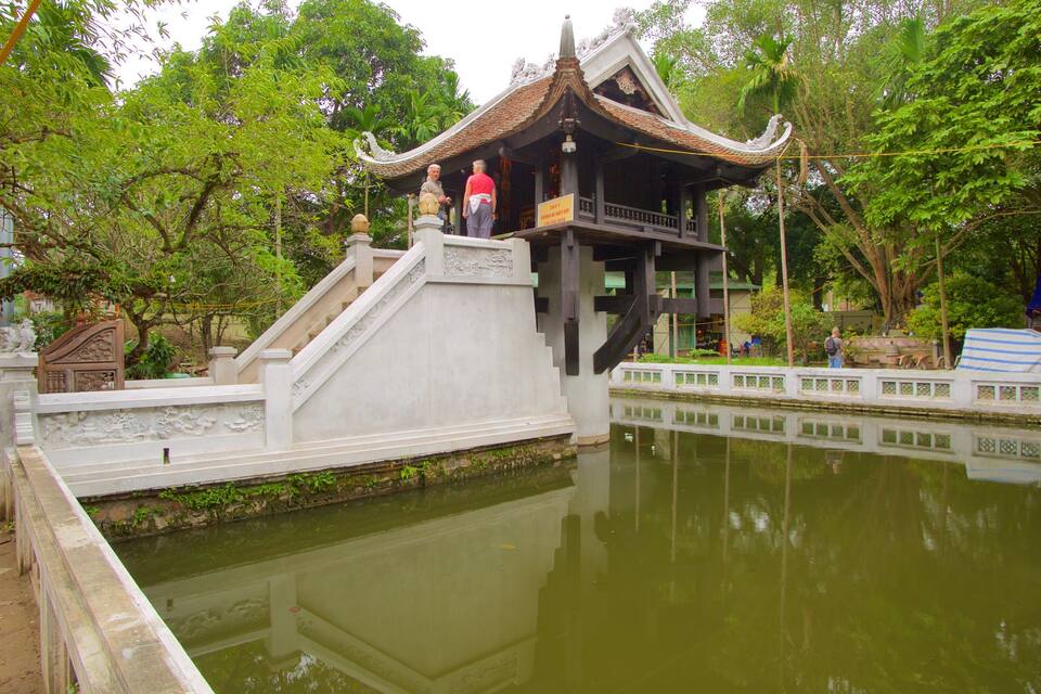 Een traditionele tempel met een betegeld dak, een stenen trap en een spiegelbeeld in het water.