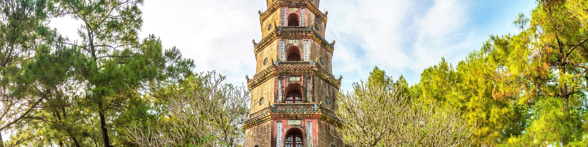 A multi-tiered pagoda surrounded by trees and a brick pathway.