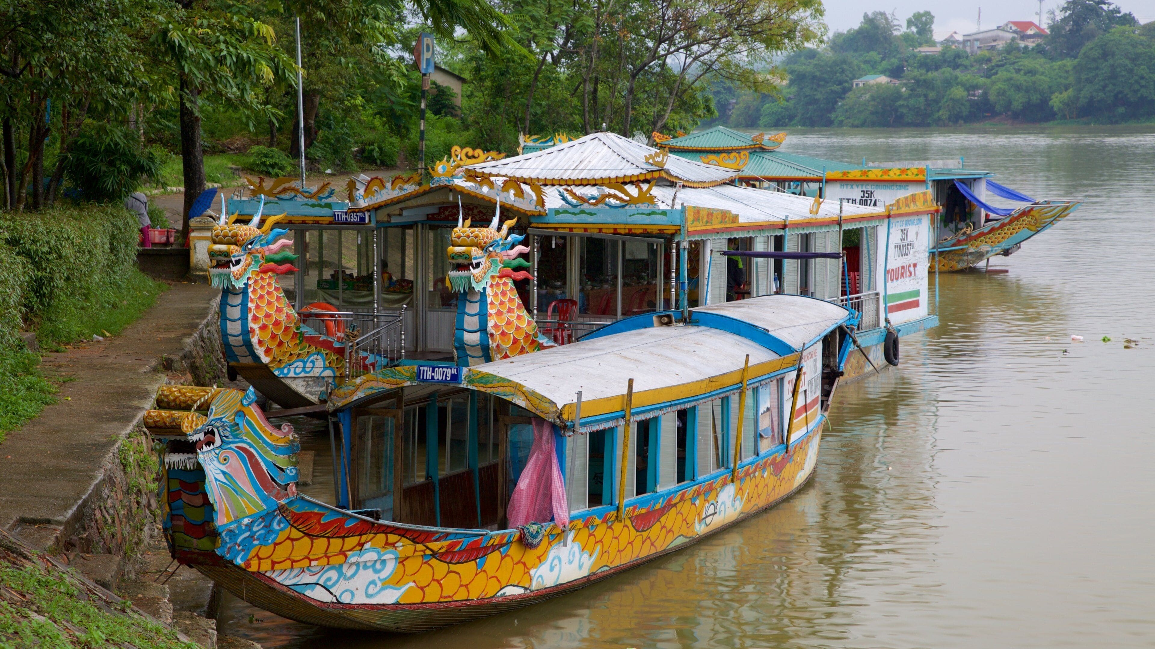 Un colorido barco dragón amarrado a la orilla del río.