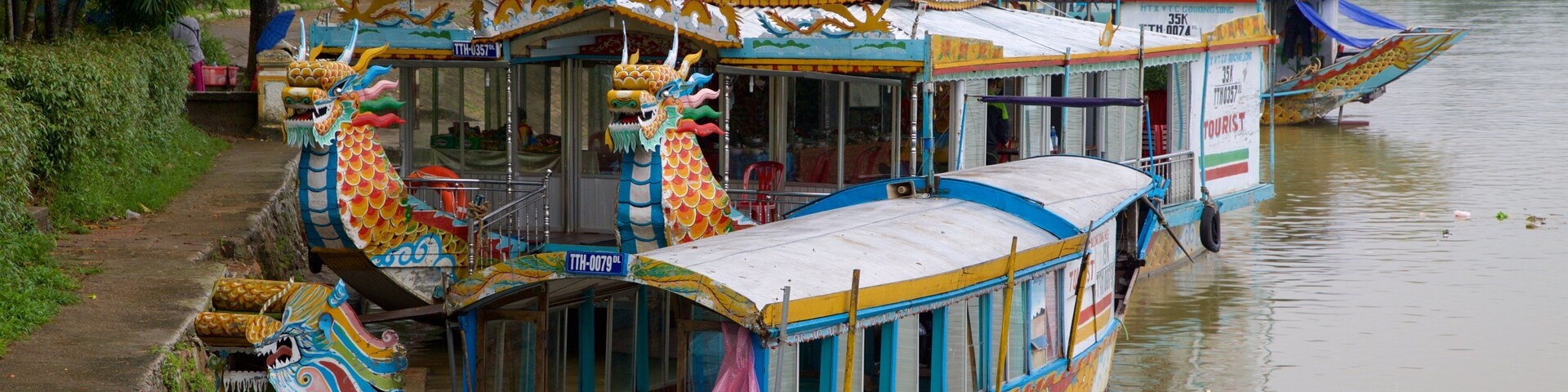 Un colorido barco dragón amarrado a la orilla del río.