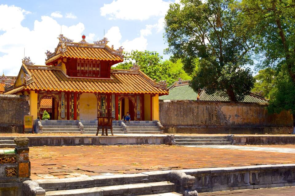 A traditional temple with ornate architecture, a stone wall, and a paved courtyard.