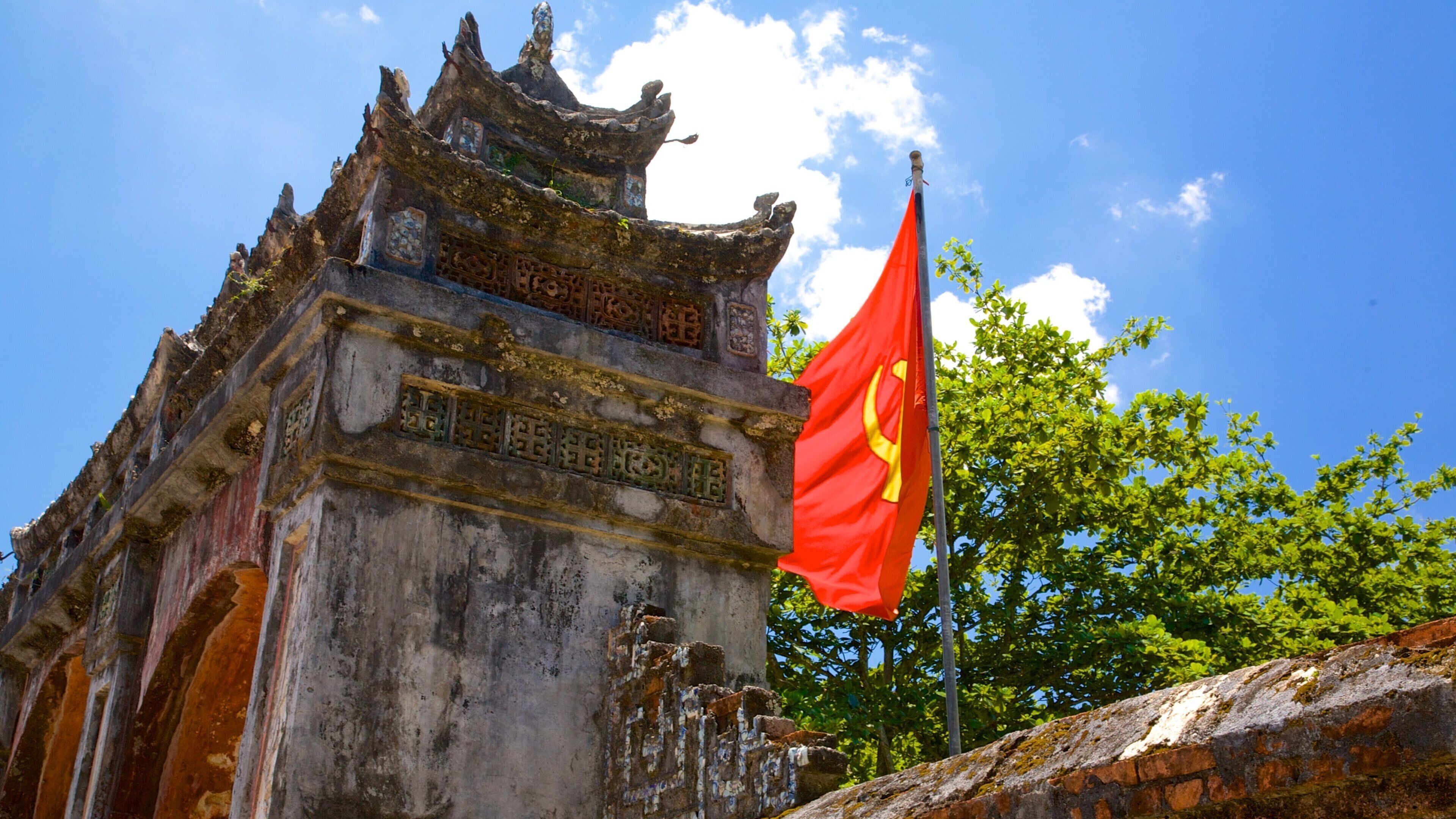 A traditional Chinese architectural structure with intricate carvings and a red flag with yellow symbols.