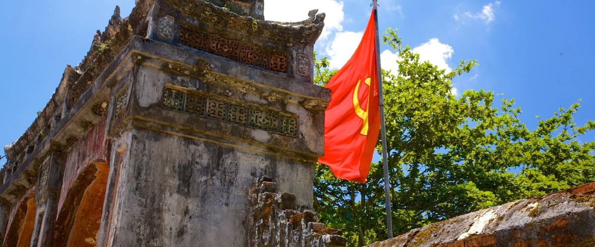 A traditional Chinese architectural structure with intricate carvings and a red flag with yellow symbols.