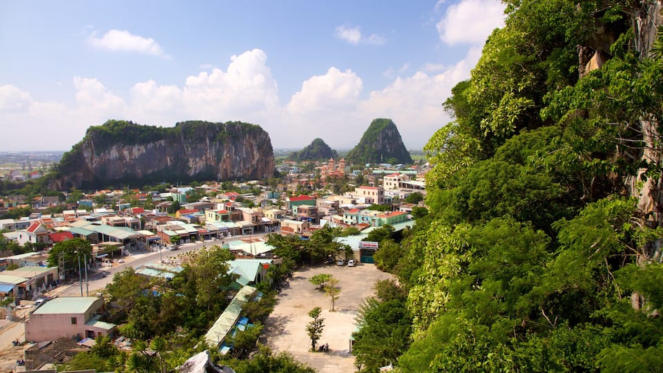 A town nestled between lush green hills and towering limestone cliffs.