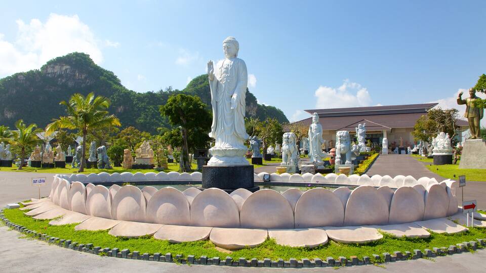 A large white statue in a garden with a mountain in the background.