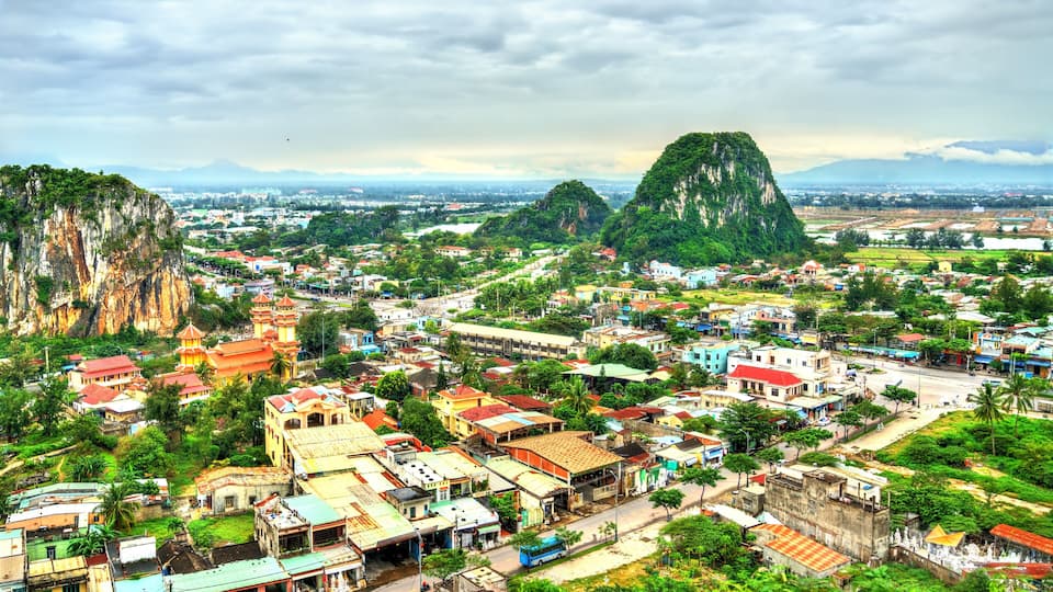 A town nestled between two large mountains, with a prominent temple and a mix of residential and commercial buildings.