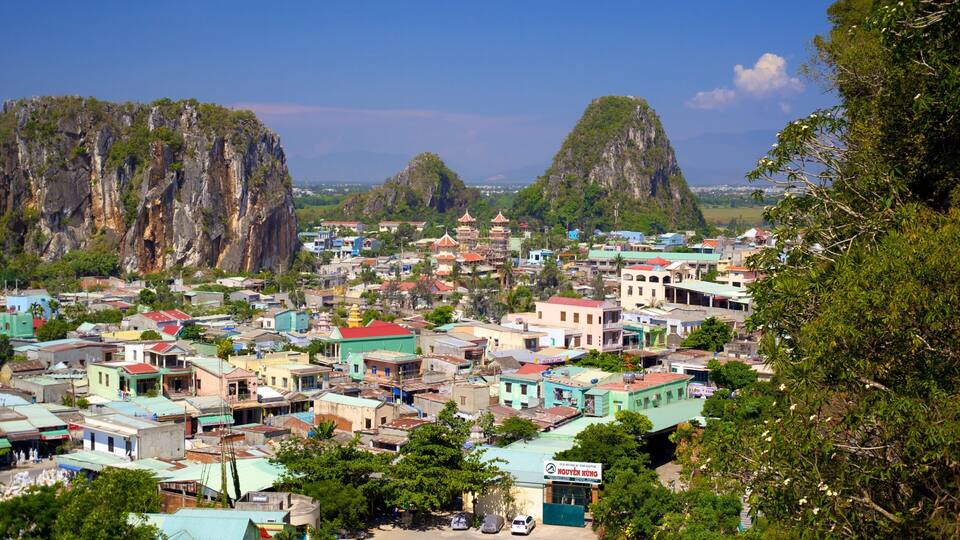 A coastal town with colorful buildings, a temple, and two prominent limestone cliffs.