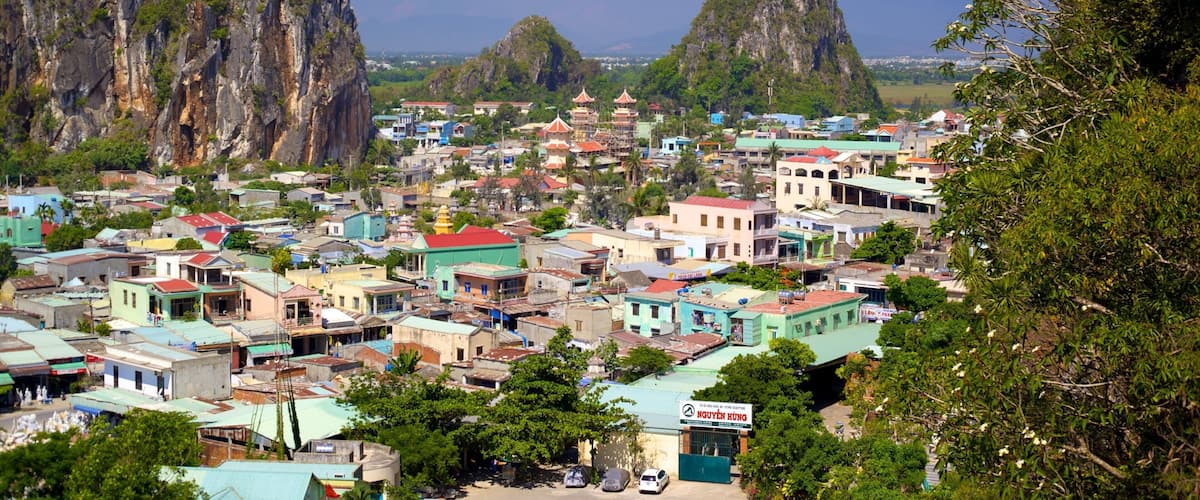 A coastal town with colorful buildings, a temple, and two prominent limestone cliffs.