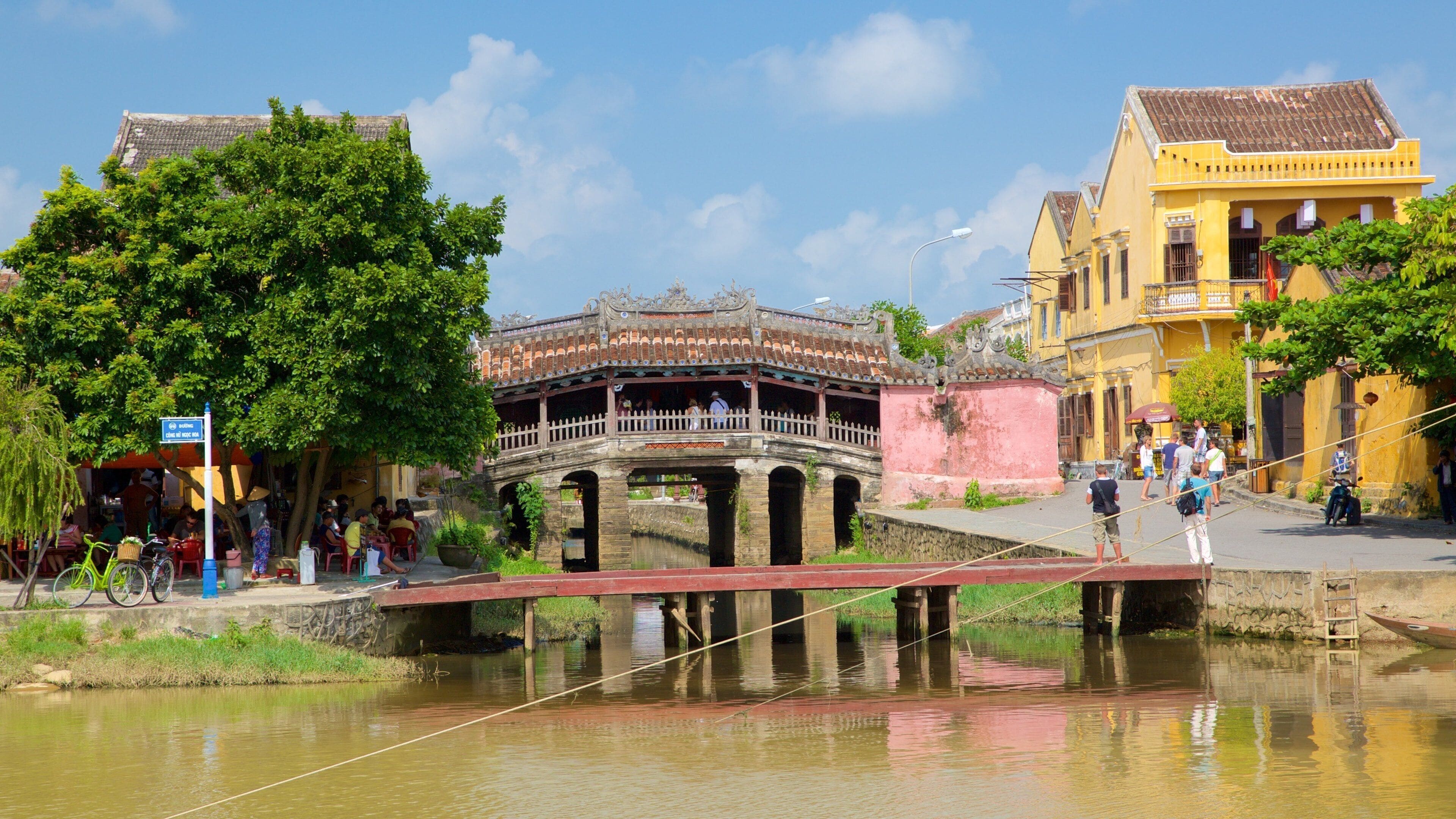 A traditional bridge over a canal, surrounded by historic buildings and lush greenery.