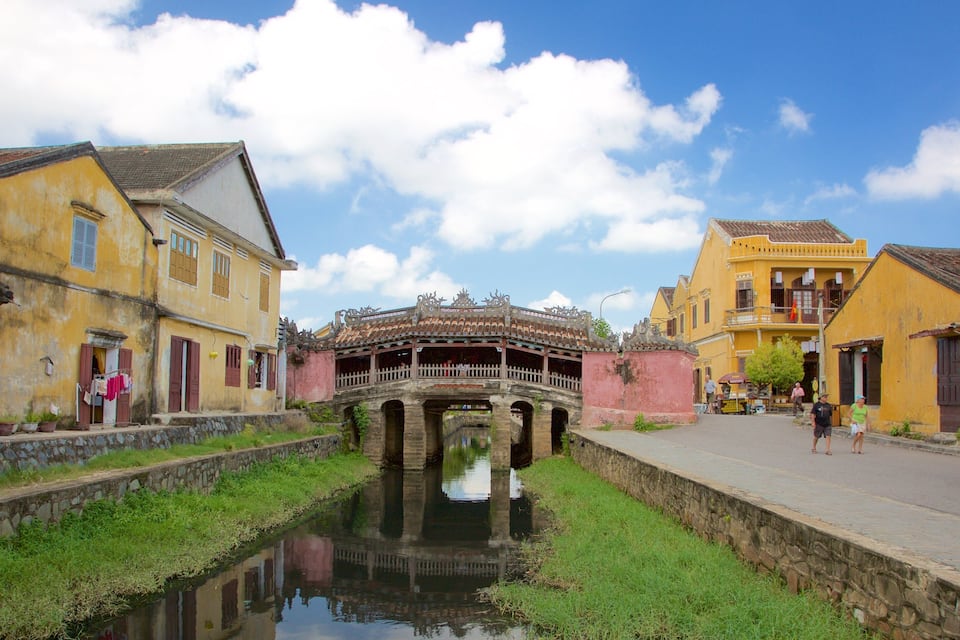 Un puente tradicional sobre un canal, rodeado de edificios históricos amarillos con contraventanas rojas.