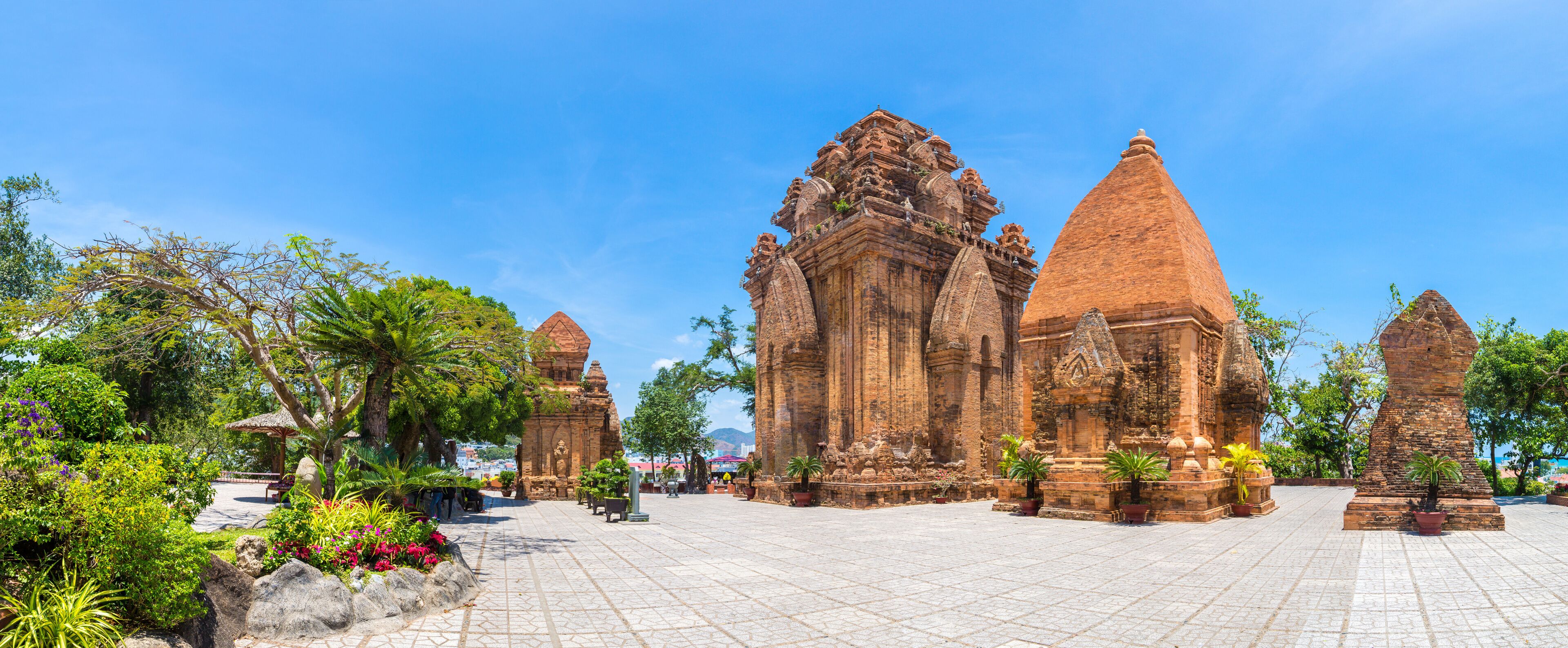 A temple complex with intricate architecture and a paved courtyard surrounded by lush greenery.