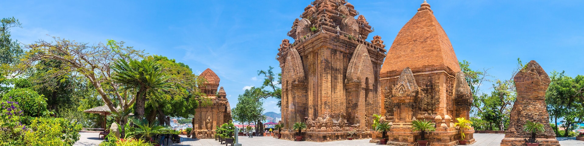 A temple complex with intricate architecture and a paved courtyard surrounded by lush greenery.
