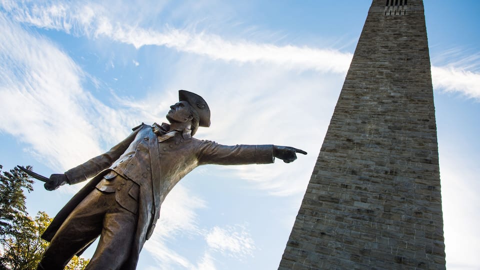 A statue with outstretched arms and a tall obelisk in the background.