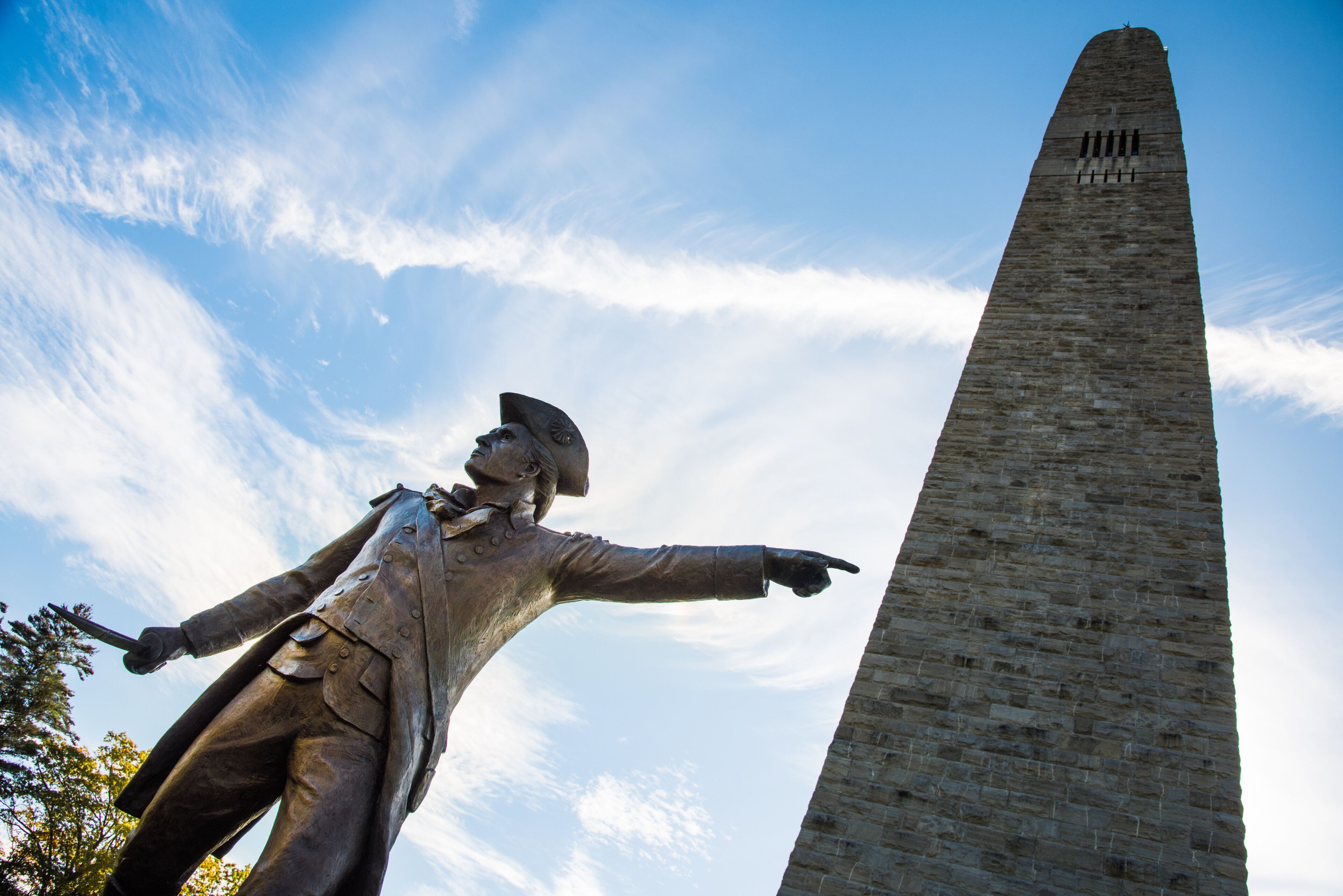 A statue with outstretched arms and a tall obelisk in the background.