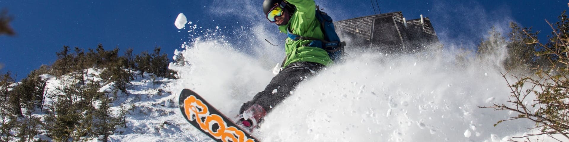 A snowboarder performing a jump with a cable car in the background.