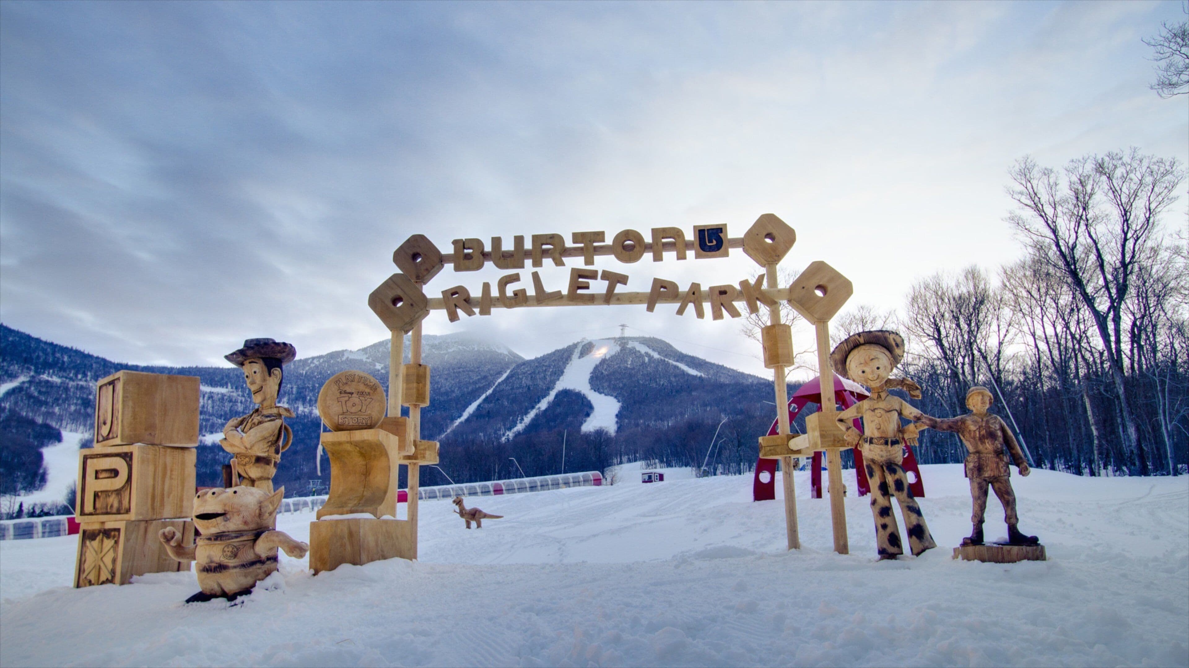 A wooden sign with 'BURTON' and 'RIGLET PARK' written on it, surrounded by wooden figures.