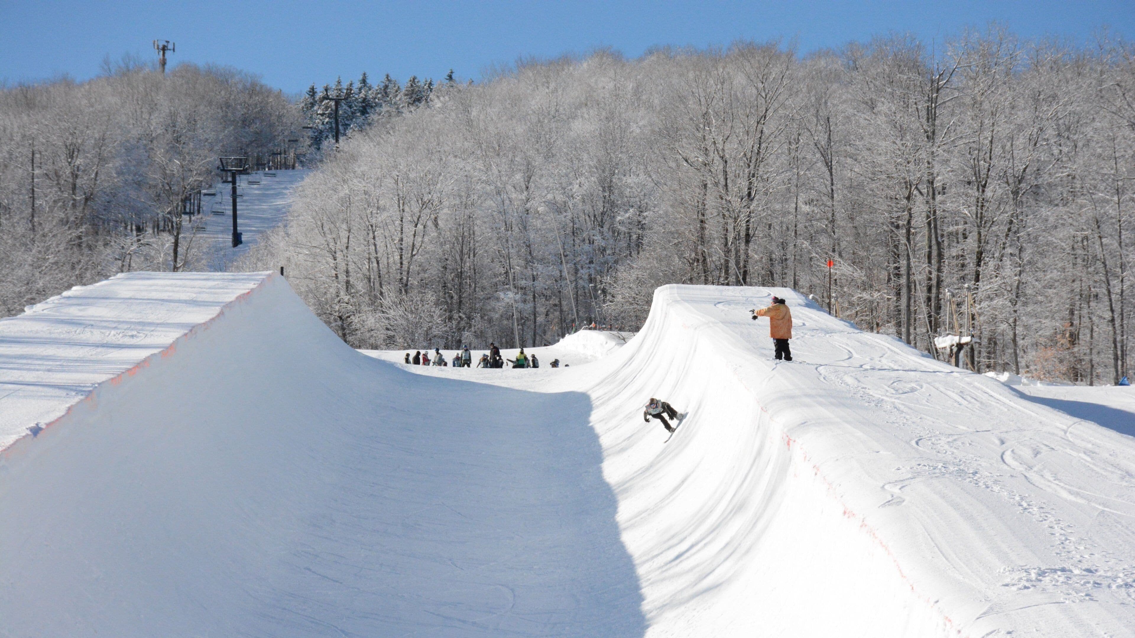 A snow-covered ski slope with a person skiing down the side.