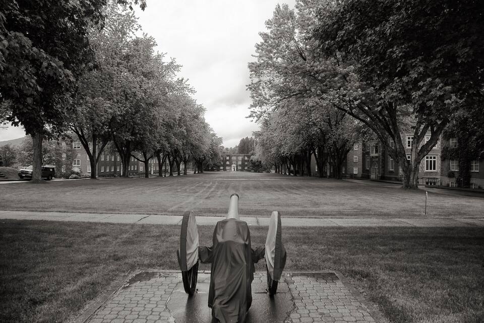 A tree-lined street with a person in a hooded jacket walking down the center.