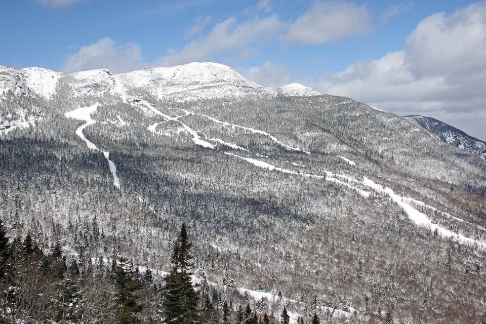 A snow-covered mountain range with a ski trail.