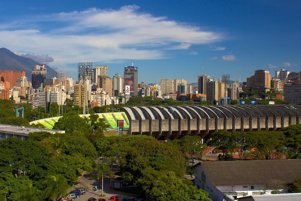 Eine Stadtansicht mit einem Stadion, Hochhäusern und einem Berg im Hintergrund.