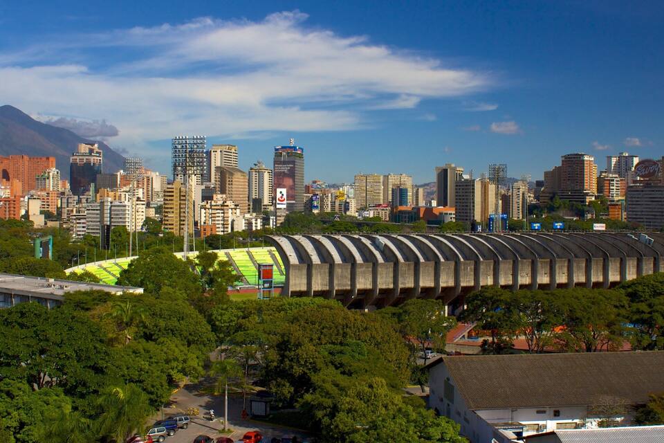 Une vue urbaine comprenant un stade, des immeubles de grande hauteur et une montagne en arrière-plan.