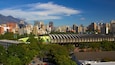Une vue urbaine comprenant un stade, des immeubles de grande hauteur et une montagne en arrière-plan.