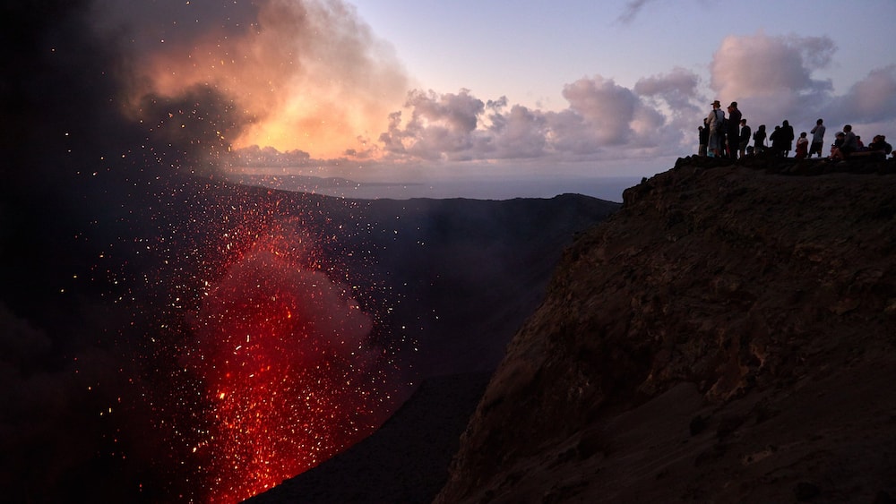 Une éruption volcanique avec de la lave qui coule le long du flanc d’une montagne.