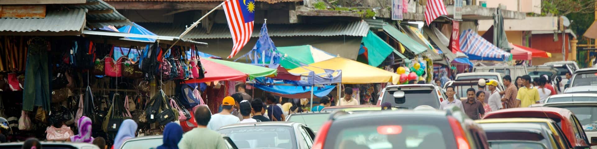 A busy street market with various stalls and cars.