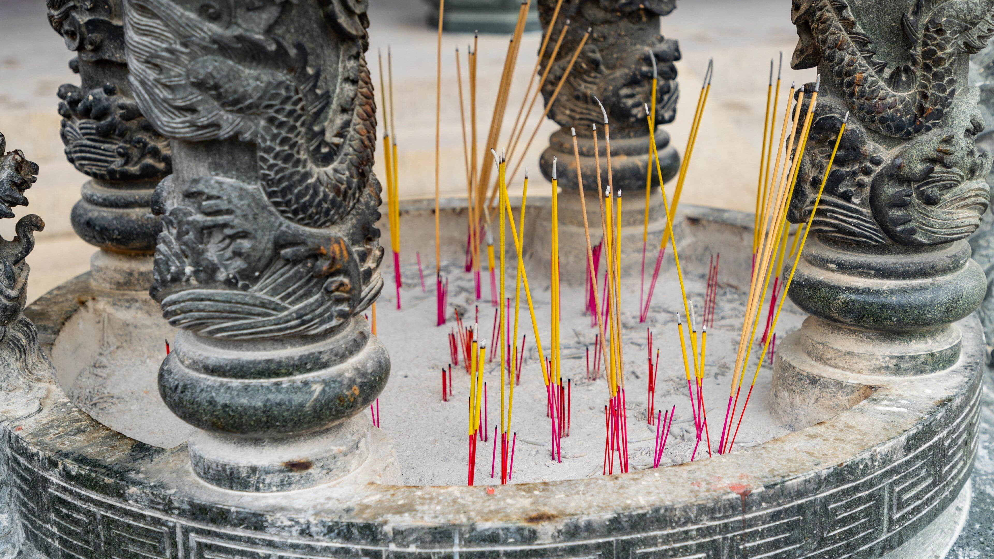 A stone altar with dragon sculptures and incense sticks.