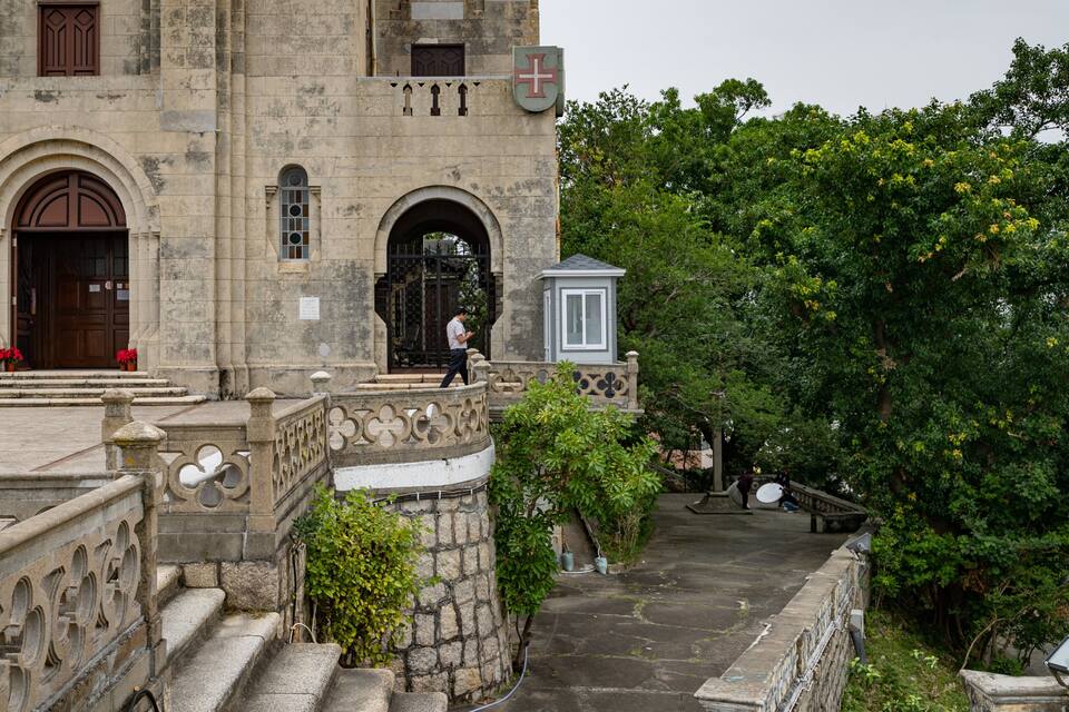 Un edificio histórico de piedra con arcos, una escalera y una bandera.