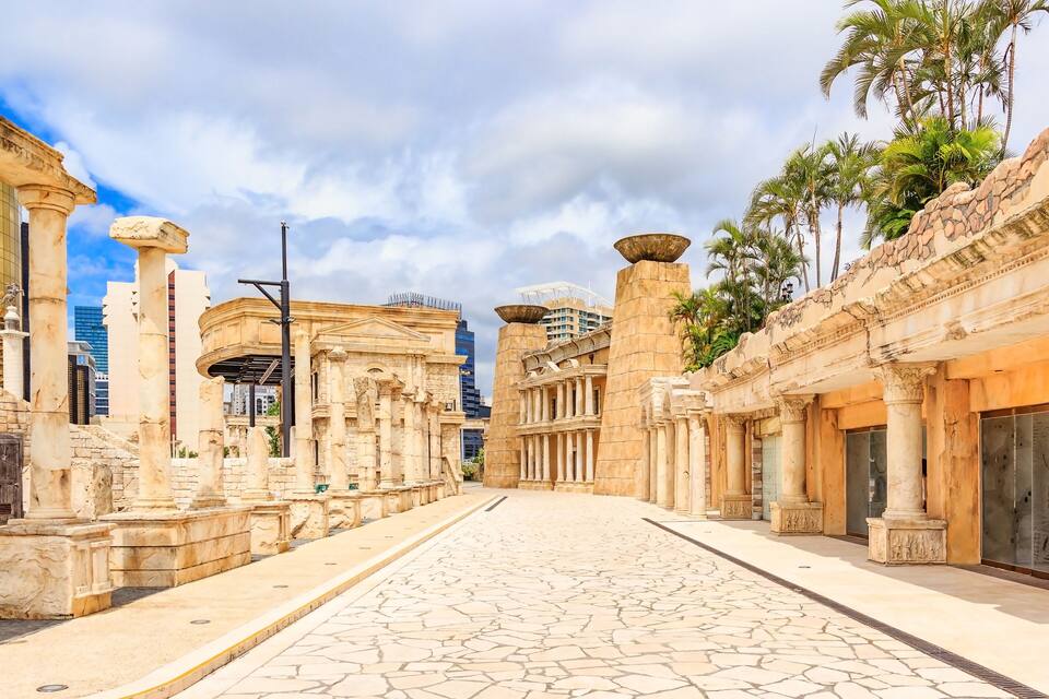 Ancient ruins with columns and a paved walkway.