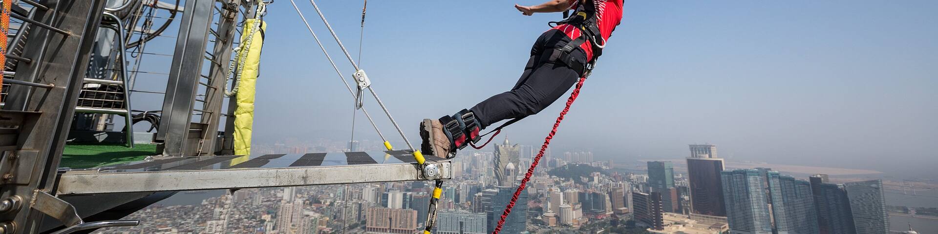 A person bungee jumping with a cityscape in the background.