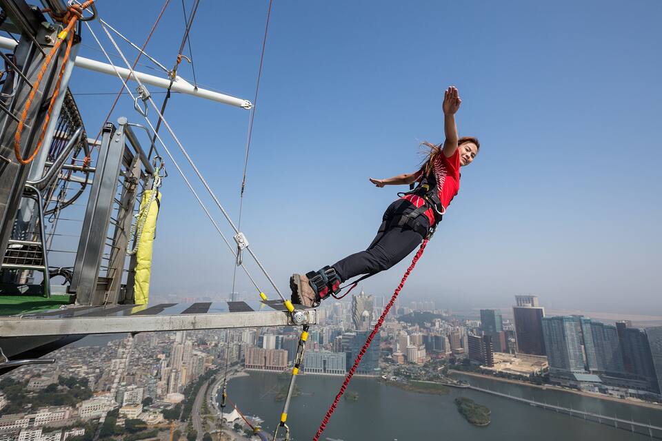 Una persona haciendo bungee jumping con un paisaje urbano de fondo.