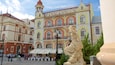 A historic building with ornate architecture, a statue, and outdoor seating.