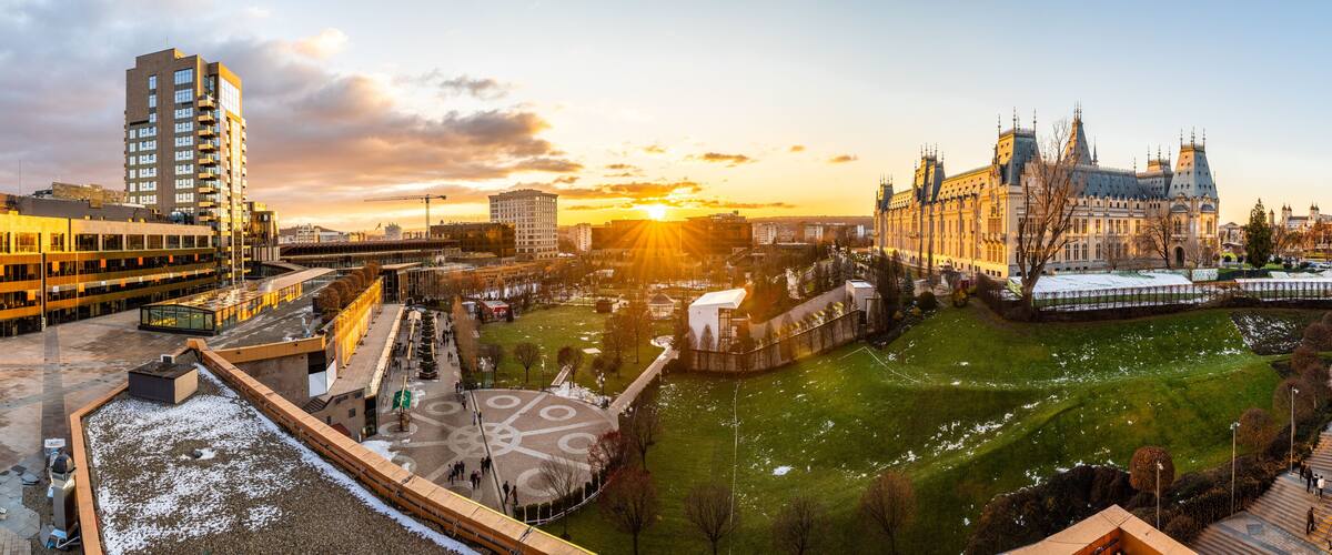 A cityscape with a historic building, modern high-rise, and a park with snow.