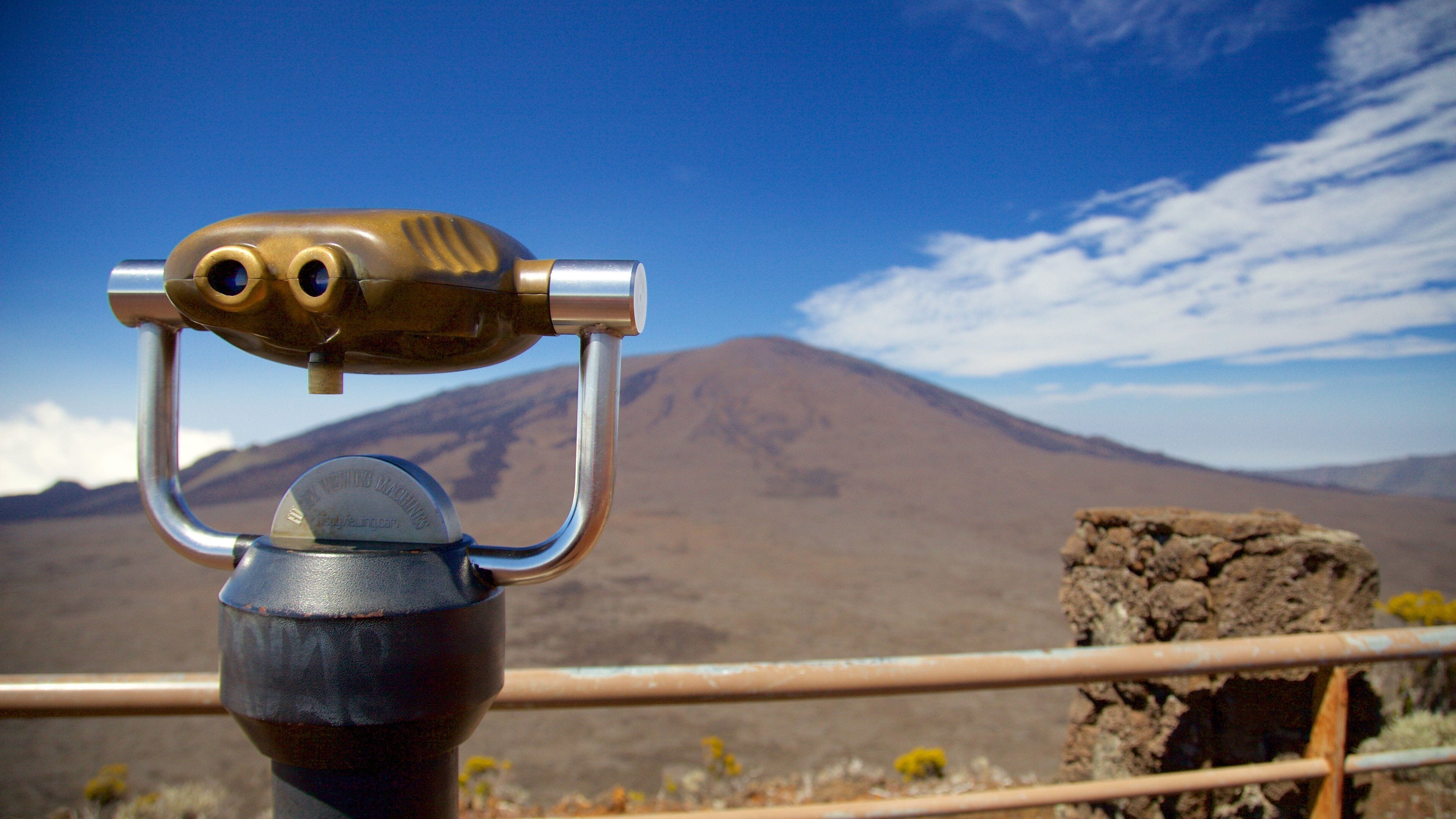 A telescope with a mountainous landscape in the background.