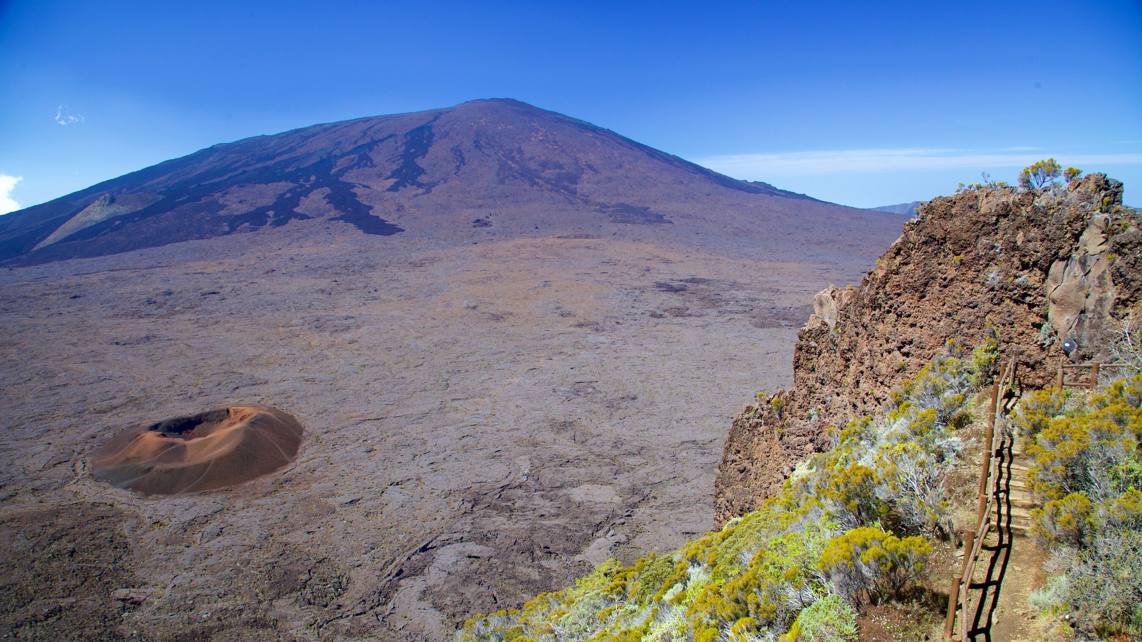 A barren volcanic landscape with a prominent mountain in the background.