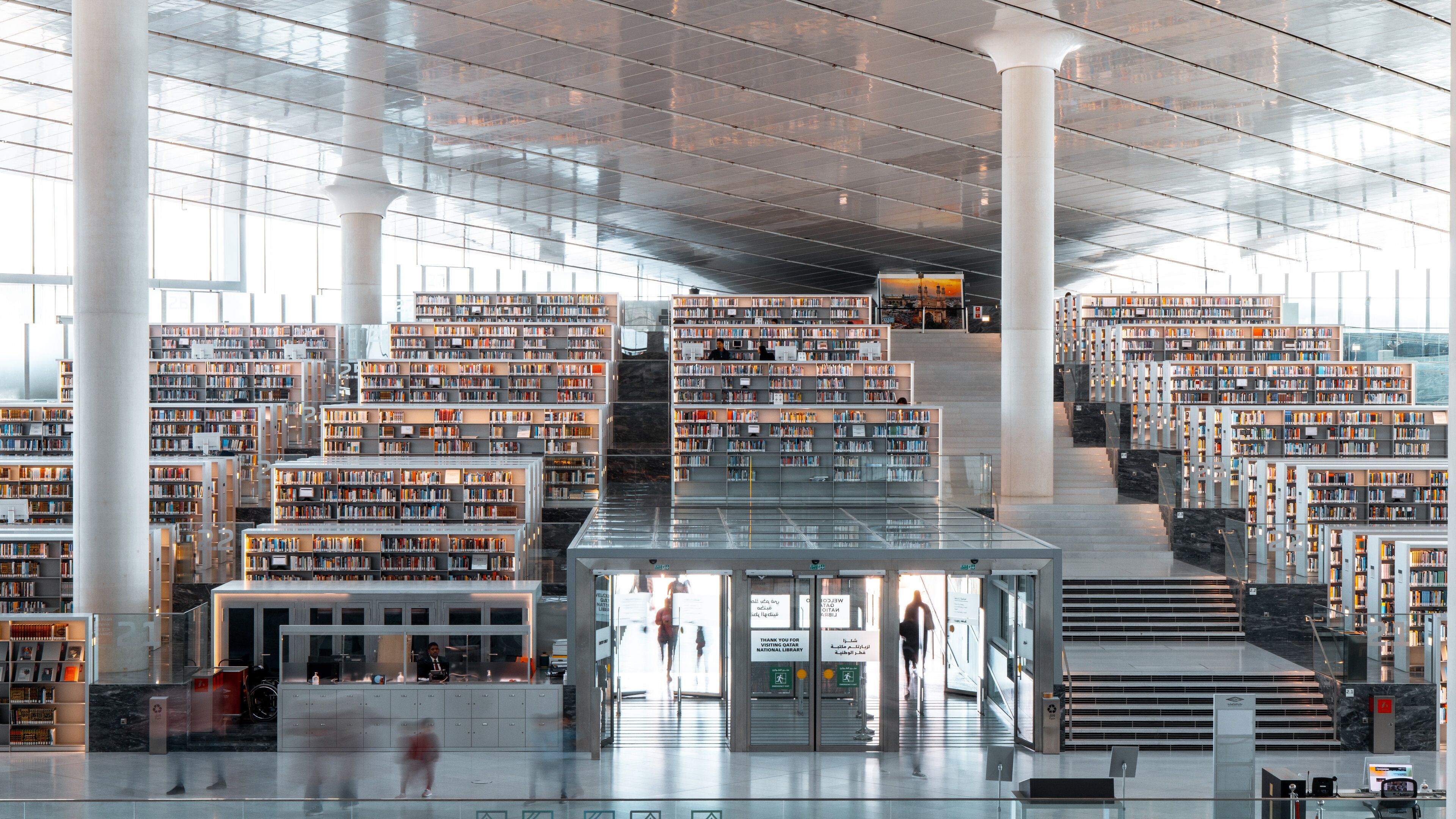 A modern library with multiple floors of bookshelves and a central staircase.