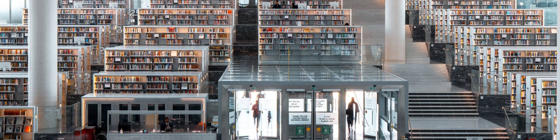 A modern library with multiple floors of bookshelves and a central staircase.