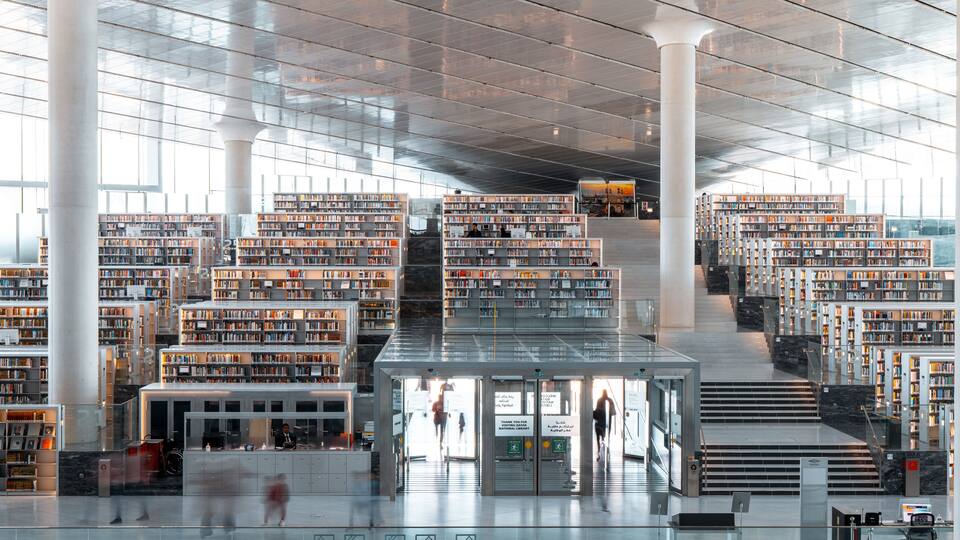A modern library with multiple floors of bookshelves and a central staircase.