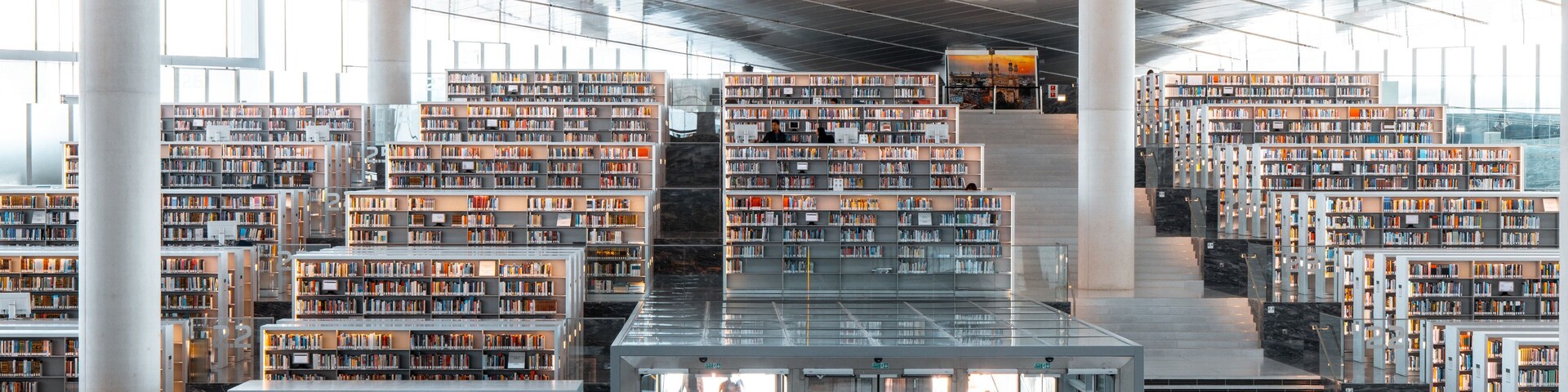 A modern library with multiple floors of bookshelves and a central staircase.