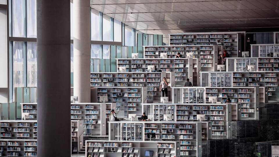 Eine moderne Bibliothek mit mehreren Ebenen Bücherregale und einem großzügigen, hellen Innenraum.