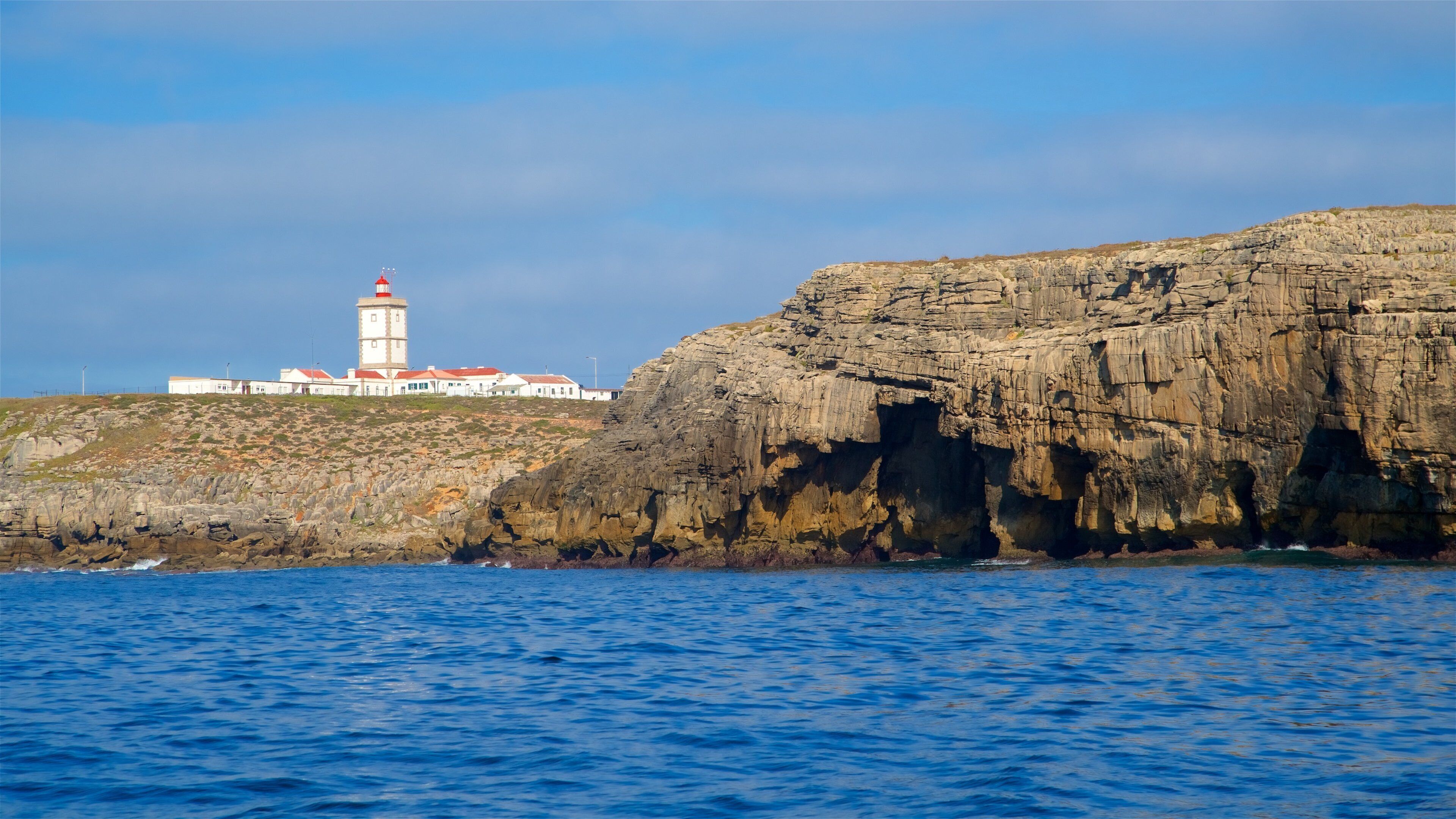 Cabo Carvoeiro which includes general coastal views, a lighthouse and rugged coastline