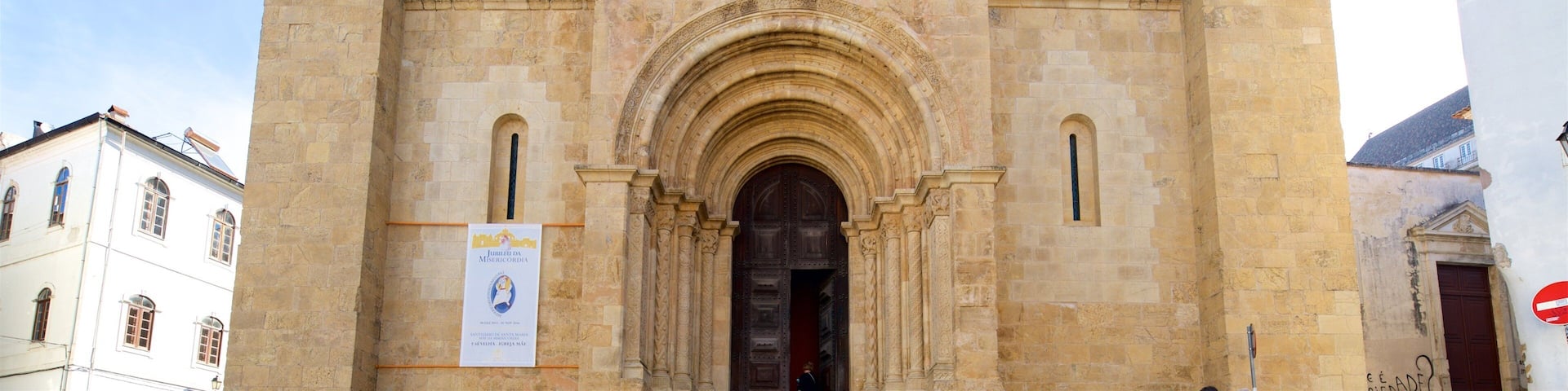 A historic stone building with a large arched entrance and a decorative window above it.