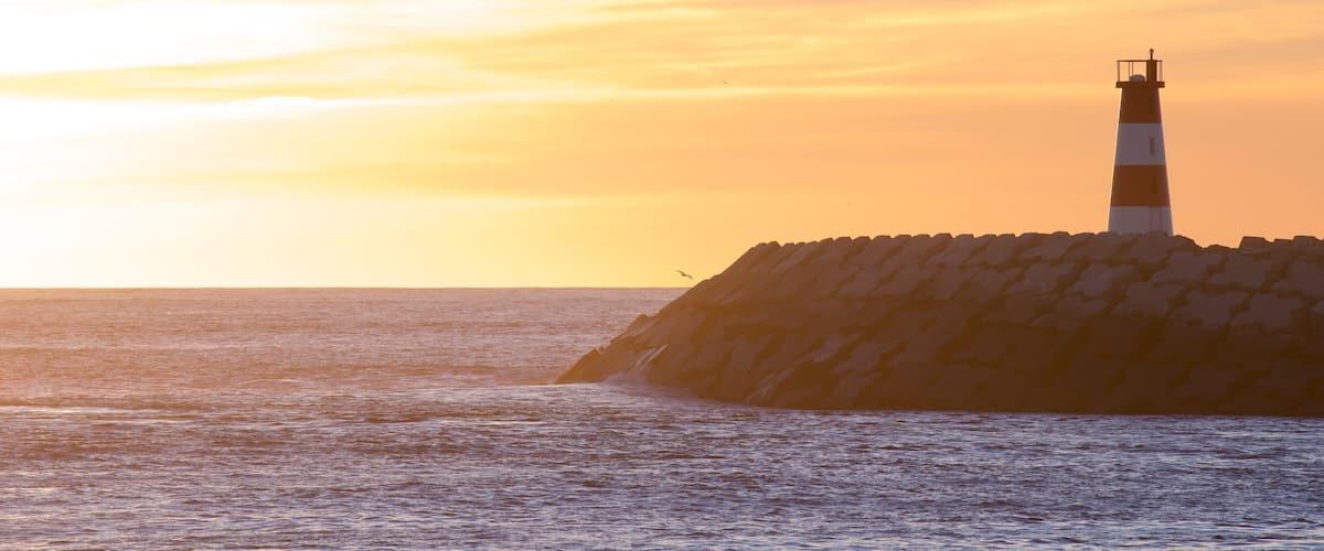 Barra Beach mettant en vedette vues littorales, coucher de soleil et phare