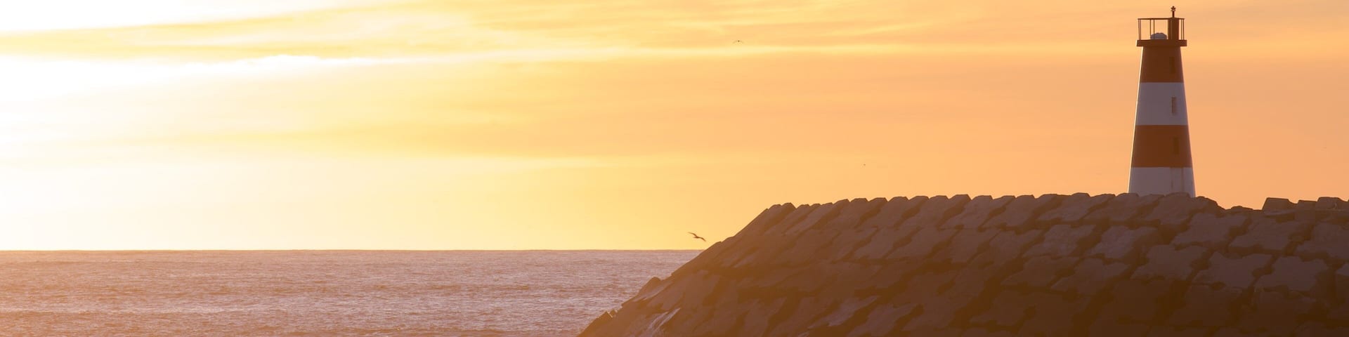 Barra Beach which includes a lighthouse, a sunset and general coastal views