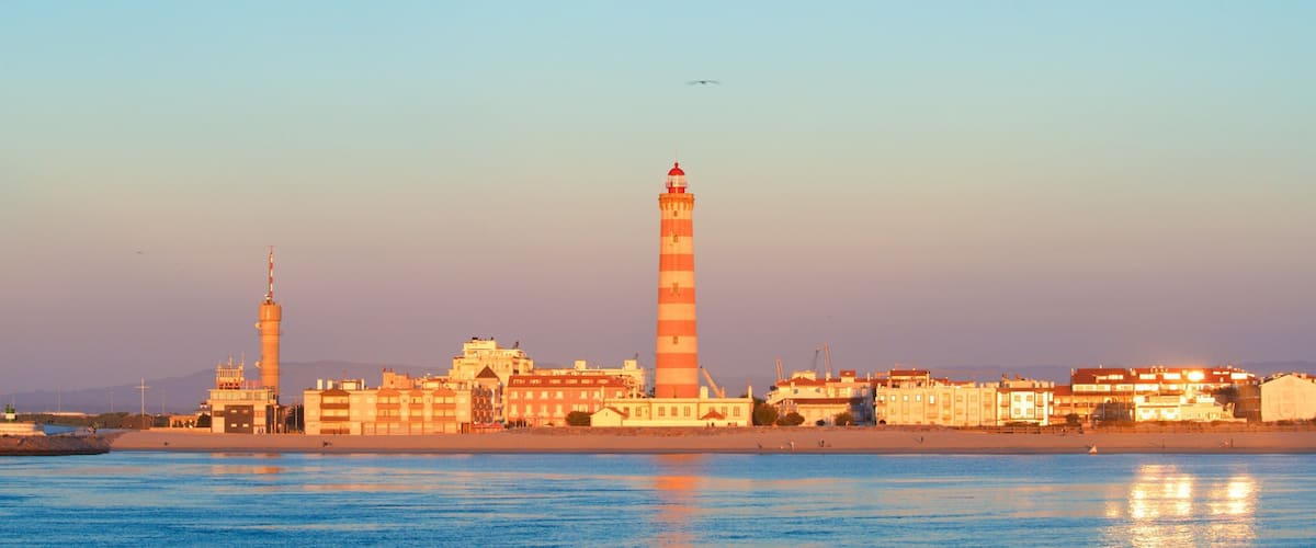 Barran uimaranta featuring majakka, rannikkokaupunki ja auringonlasku