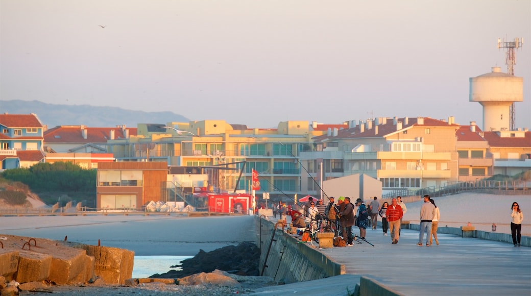 Barra Beach featuring a sunset and a coastal town as well as a small group of people