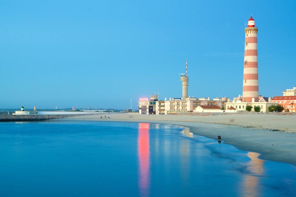 A coastal scene with a lighthouse, beach, and buildings.