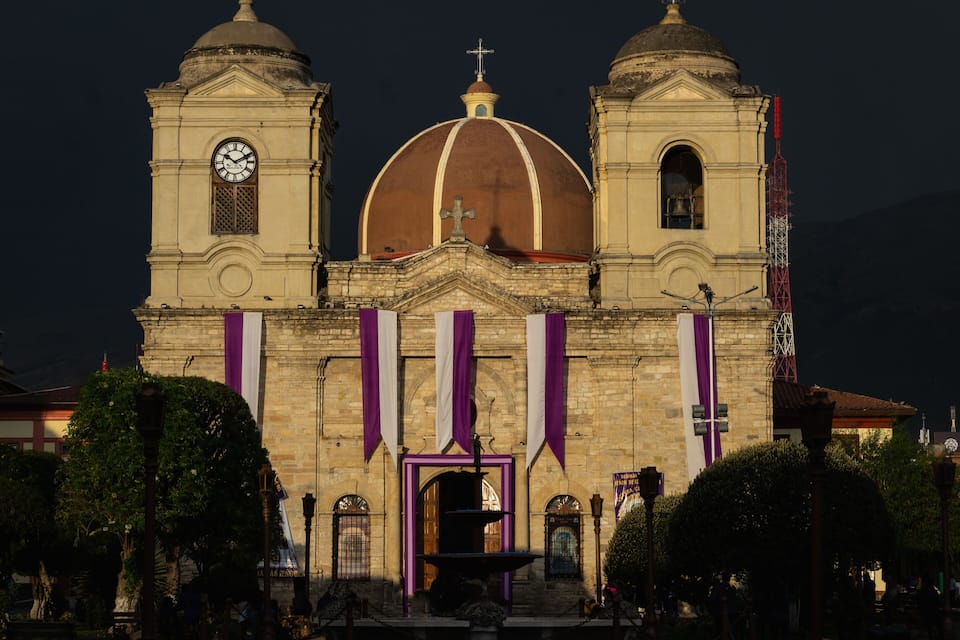 Eine historische Kirche mit zwei Glockentürmen und einer großen Kuppel, geschmückt mit violetten Bannern.